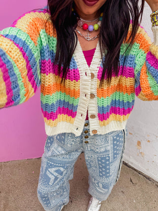 Brighten up any gloomy day with this vibrant, eye-catching rainbow cardigan! Knit with a chunky, open-stitch texture, this cardigan balances a playful, multi-colored aesthetic with effortless cozy comfort.